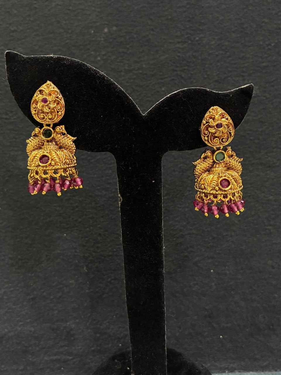 Jhumka earrings feature peacock motifs and dangling bead drops