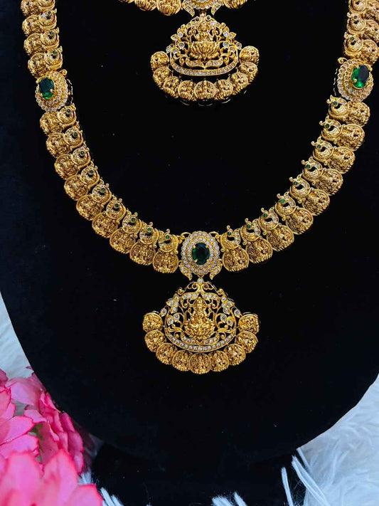 Bridal temple jewelry set features Lakshmi coin motifs and emerald stone