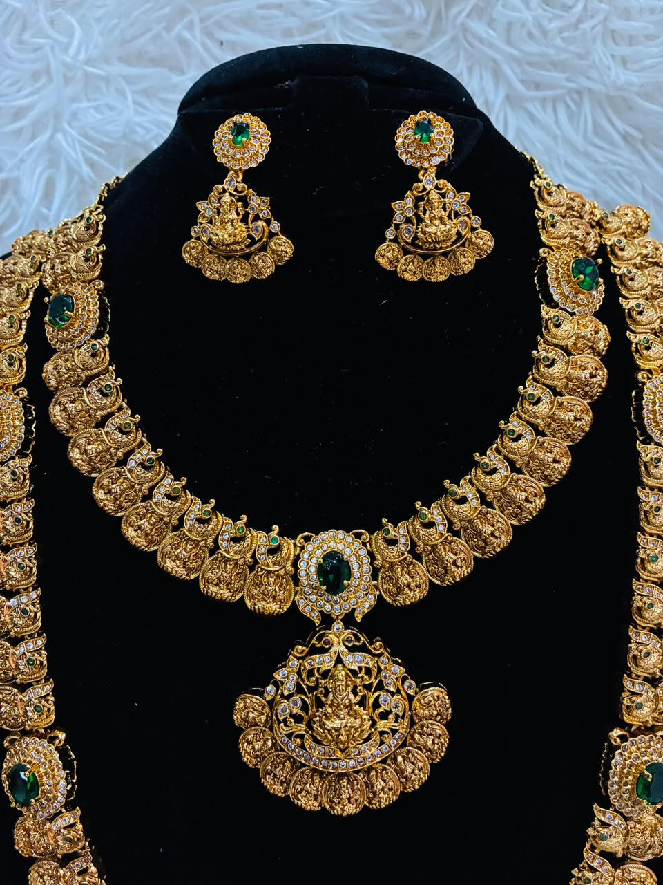 Bridal temple jewelry set features Lakshmi coin motifs and emerald stone