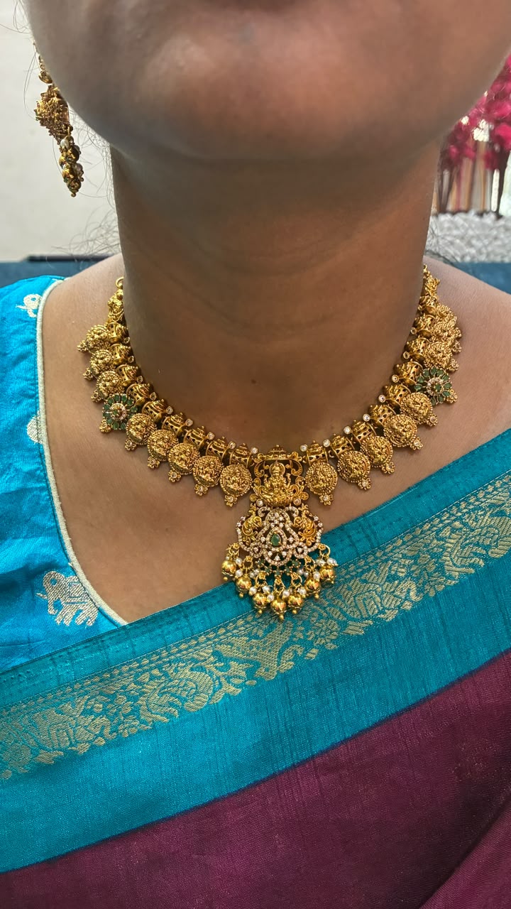 Temple necklace features intricate Lakshmi motifs, emerald stones