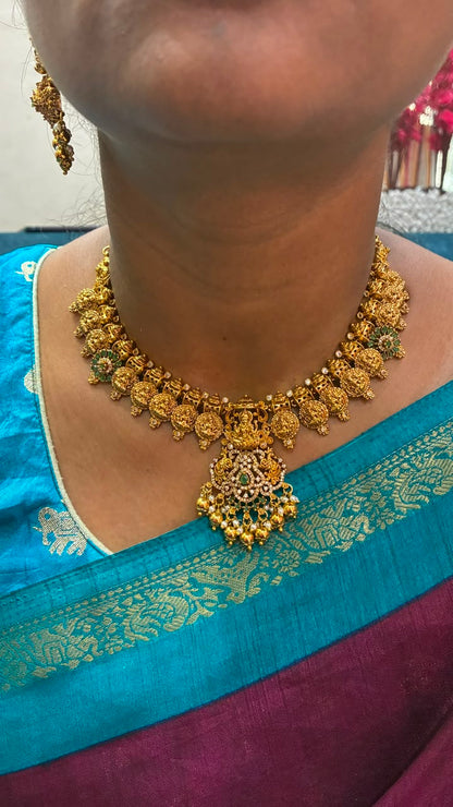 Temple necklace features intricate Lakshmi motifs, emerald stones