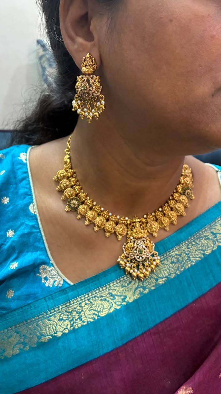 Temple necklace features intricate Lakshmi motifs, emerald stones