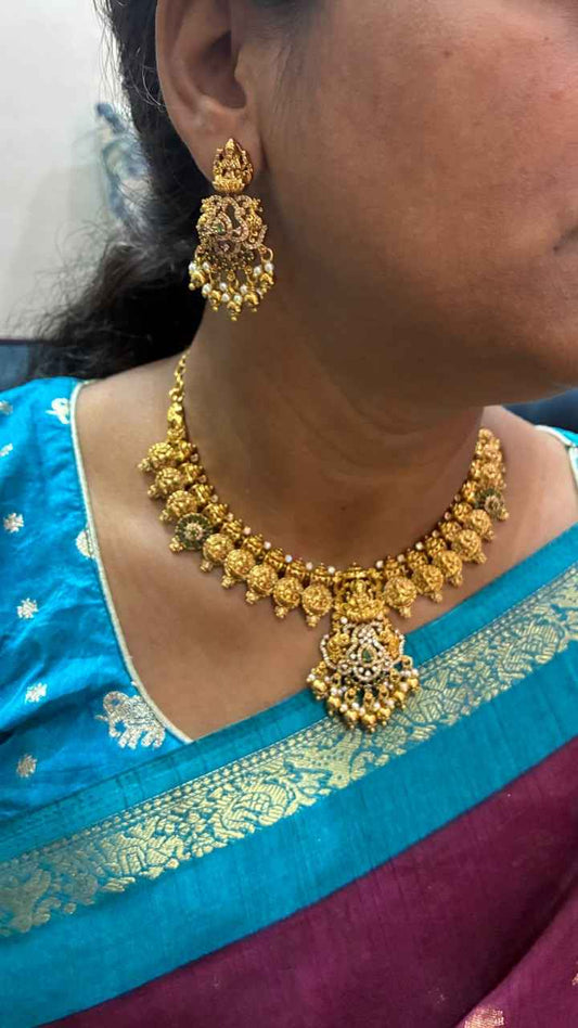 Temple necklace features intricate Lakshmi motifs, emerald stones