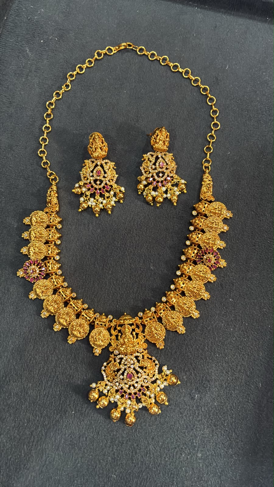 Temple necklace features intricate Lakshmi motifs, emerald stones